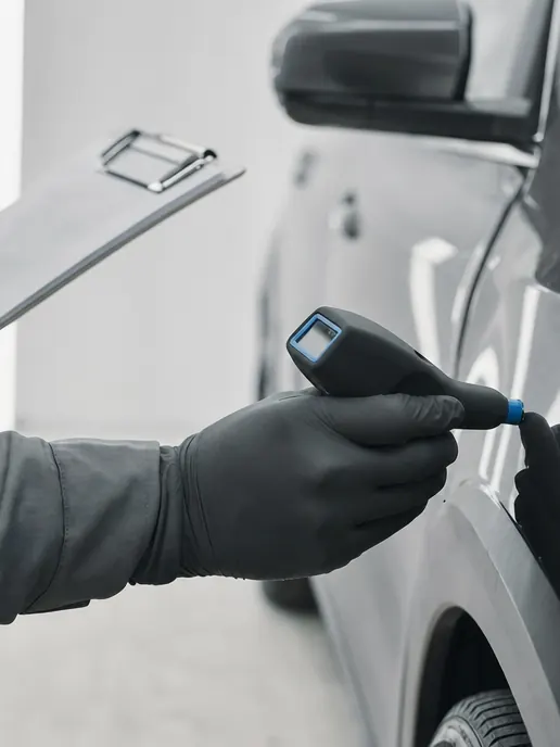Un inspector midiendo el espesor de pintura de un coche
